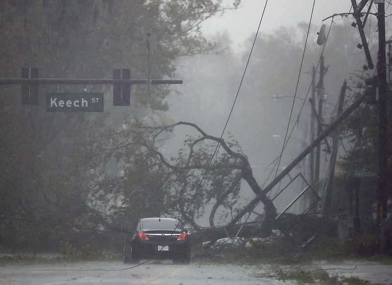 A car drives past a downed tree as Hurricane Matthew moves through Daytona Beach, Fla. Friday. (AP Photo/Charlie Riedel)