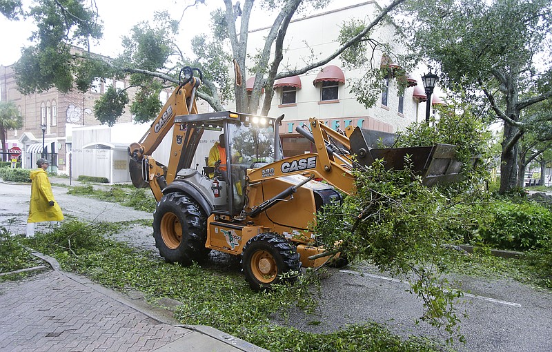 As Hurricane Matthew moves through the area, workers clear tree limbs and debris from a street Friday, Oct. 7, 2016, in Cocoa, Fla. Matthew weakened slightly to a Category 3 storm with maximum sustained winds near 120 mph.