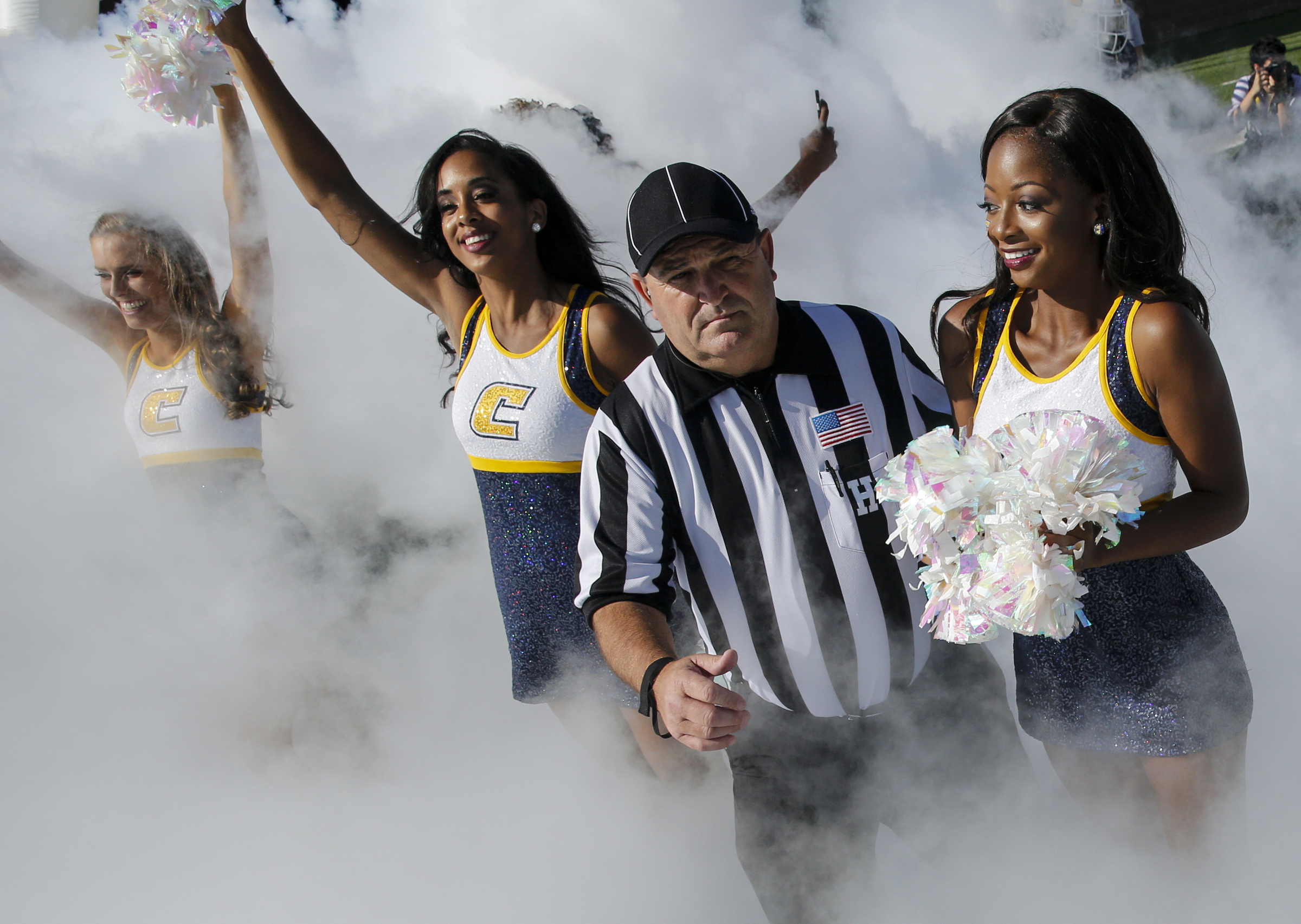 An official tries to get through cheerleaders as the UTC team takes the field during the Mocs' home football game against the Mercer Bears at Finley Stadium on Saturday, Oct. 8, 2016, in Chattanooga, Tenn.