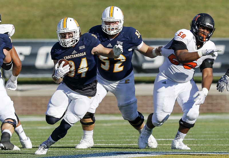 UTC running back Derrick Craine takes the ball ahead of teammate Jacob Revis and Mercer defensive lineman Dorian Kithcart (58) during the Mocs' home football game against the Mercer Bears at Finley Stadium on Saturday, Oct. 8, 2016, in Chattanooga, Tenn.