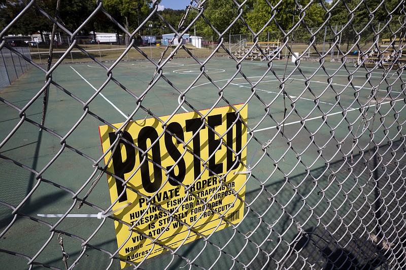 A "No Trespassing" sign is posted on the fence of the Lincoln Park tennis courts on Tuesday, Oct. 4, 2016, in Chattanooga, Tenn. Erlanger Hospital controls the historically black park, and nearby residents say that security has been forcing people from the neighborhood off of the park premises but allowing white children from outside the neighborhood to play there.