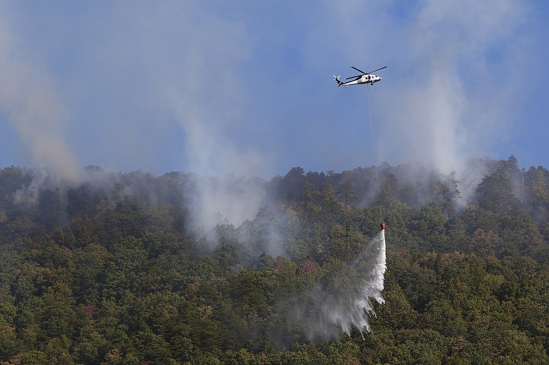 Emergency personnel use a helicopter to help put out a forest fire that is threatening a neighborhood off of Rocky Ledge Road in Falling Water, Tenn., on Monday, Oct. 10, 2016. A brush fire that started this past weekend has been difficult to extinguish due to dry conditions and strong winds.