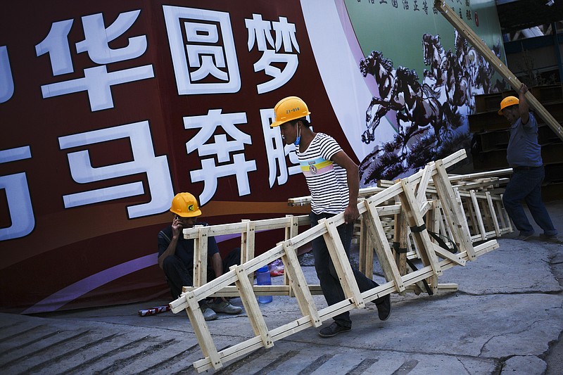 
              In this Sept. 5, 2016 photo, workers carry wooden latter past by a Chinese government's propaganda "China Dream" billboard on display outside a construction side in Beijing. Chinese authorities unveiled plans on Monday, Oct. 10, 2016 to let companies use debt-for-equity swaps to cut soaring debt levels that economists warn might hamper the country's already slowing growth. (AP Photo/Andy Wong)
            