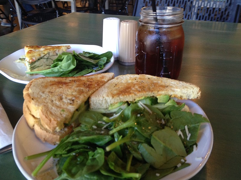The spicy chicken sandwich, made with sliced chicken, avocado, cucumber and spicy mayonnaise on grilled sourdough, is served with a choice of spinach side salad or chips at The Meeting House in Red Bank. The veggie quiche, in back, is flavored with spinach, tomato, onion and cheddar.
