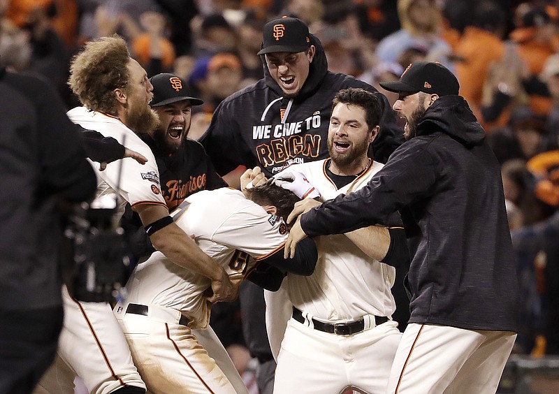 San Francisco Giants' Joe Panik, center bottom, is congratulated by teammates after hitting a double to score Brandon Crawford during the thirteenth inning of Game 3 of baseball's National League Division Series against the Chicago Cubs in San Francisco, Monday, Oct. 10, 2016. The Giants won 6-5.
