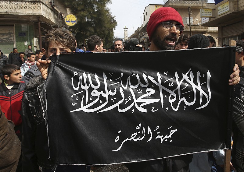 
              FILE- In this March 1, 2013 file photo, anti-Syrian President Bashar Assad protesters hold the Jabhat al-Nusra flag, as they shout slogans during a demonstration, at Kafranbel town, in Idlib province, northern Syria. Insurgent groups like Hezbollah and the Islamic State group in Syria have learned how to weaponize surveillance drones and use them against each other, adding a new twist to the country’s civil war, a U.S. military official and others say. (AP Photo/Hussein Malla, File)
            