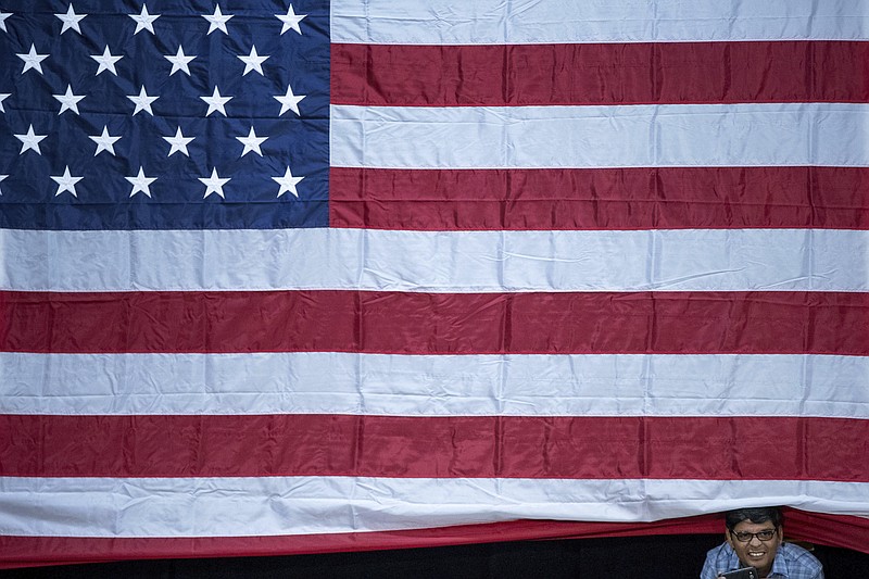 
              A man sticks his head out from under a large American flag as Democratic presidential candidate Hillary Clinton finishes a rally at Miami Dade College in Miami, Tuesday, Oct. 11, 2016. (AP Photo/Andrew Harnik)
            