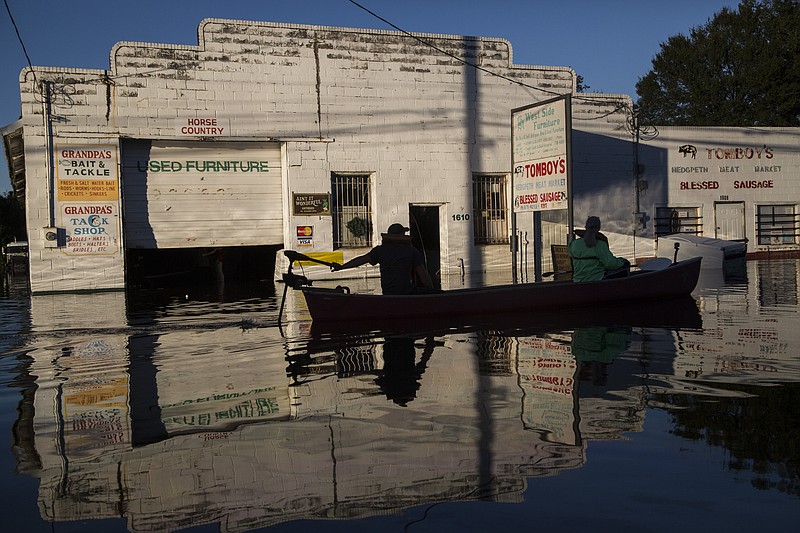 
              Ryan Christian and Delores Miller canoe down West 5th Street after checking on Miller's elderly mother's home in downtown Lumberton after Hurricane Matthew caused downed trees, power outages and massive flooding along the Lumber River, Tuesday, Oct. 11, 2016 in Lumberton, NC. (Travis Long/The News & Observer via AP)
            