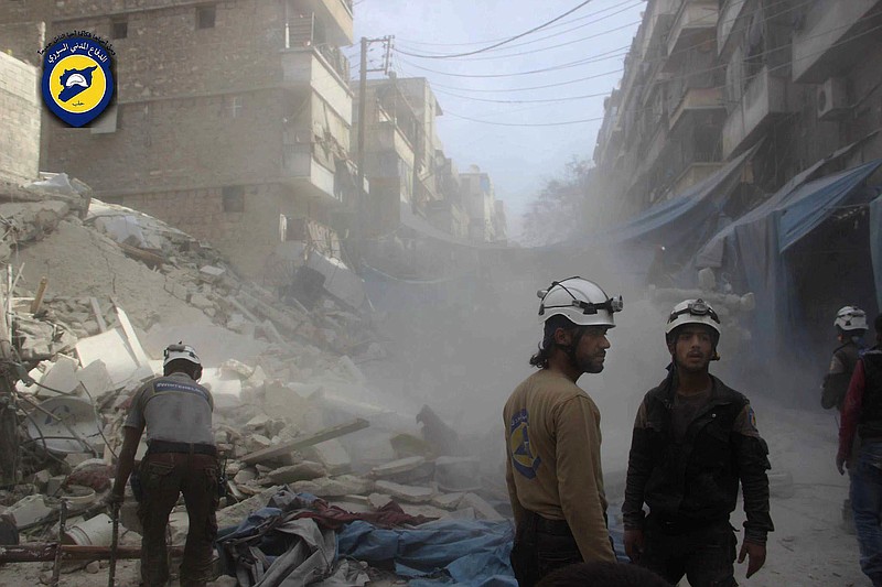 In this picture provided by the Syrian Civil Defense group known as the White Helmets, Syrian Civil Defense workers search through the rubble in rebel-held eastern Aleppo, Syria, Wednesday, Oct. 12, 2016. A spectacular air raid in Syria's besieged rebel-held Aleppo city hit the territory's biggest market Wednesday, killing at least 15, obliterating several stores and levelling buildings, activists and a witness said. The raid came a day after at least 41 people dead, including at least five children, were killed when aircraft bombed several neighborhoods in the eastern Aleppo area, overwhelming rescue workers who continued a day later Wednesday to search for survivors under the rubble. (Syrian Civil Defense- White Helmets via AP)