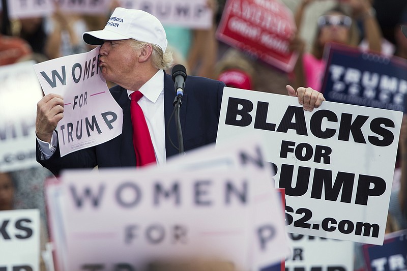 
              Republican presidential candidate Donald Trump kisses a "Women for Trump" sign during a campaign rally, Wednesday, Oct. 12, 2016, in Lakeland, Fla. (AP Photo/ Evan Vucci)
            