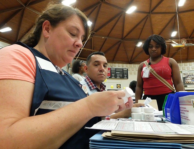 At a dispensing table, Gretchen Miller, left, and Zeke Garcia prepare medicine for patient Chelauna Sterling during Friday's Emergency Response exercise at Hixson High School.