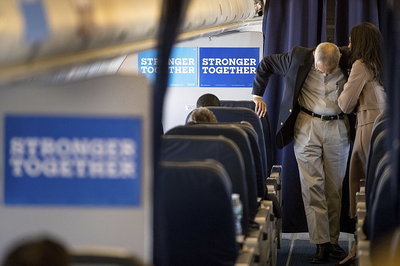 John Podesta, left, campaign manager for Hillary Clinton, and senior aide Huma Abedin huddle aboard Clinton's campaign plane while traveling for a rally last week.