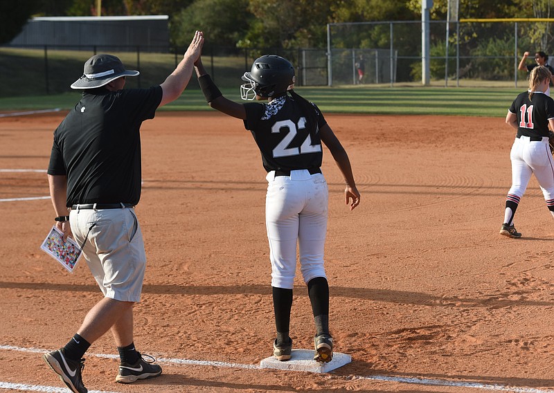 Ridgeland's Kiera Foster (22) gets a congratulatory hand slap from assistant coach Justin Carruth at first during the first of two games Tuesday night. The Panthers defeated Woodward Academy in 11-1, and 13-0 in the GHSA Class AAAA second round playoffs at home.