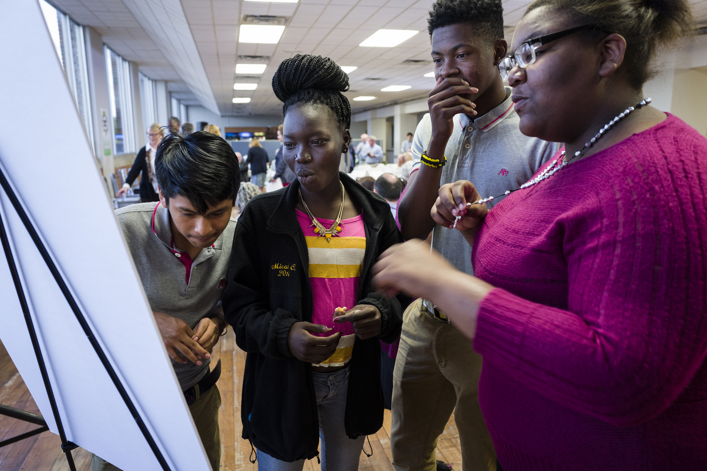 Howard School students Nelson Hernandez, Sunday Dau, Menachin Brown, and Natacha Peace, from left, react to a display that ranks the percentage of teachers at their school classified as "least effective" against other schools before a forum hosted by the Times Free Press to discuss education in Hamilton County on Tuesday, Oct. 18, 2016, in Chattanooga, Tenn. A panel of educators and education administrators answered questions about teacher quality, preparation, and solutions to education issues facing the district.