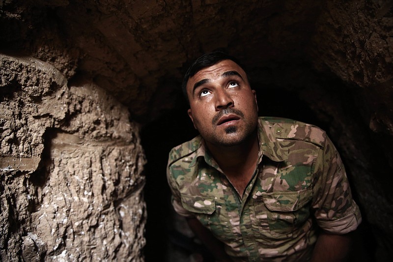 
              A peshmerga fighter looks out of the entrance of an underground tunnel built by Islamic State fighters, Tuesday, Oct. 18, 2016. The Kurdish forces found the tunnel in the town of Badana that was liberated from the Islamic State group on Monday. The fighters built tunnels under residential areas so they could move without being seen from above to avoid airstrikes. (AP Photo/Bram Janssen)
            