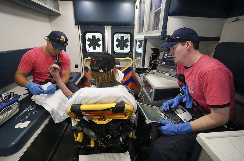 Hamilton County EMS Station 9 Paramedics Joseph Moyer, left, and Ian Stearns, right, take vitals before transporting a sick patient from an Eastlake area residence to Parkridge Medical Center on Thursday. While this patient was not suffering from an overdose, area EMS workers have seen an increase in drug ODs, and have had to use Narcan, an anti-overdose drug, more frequently.