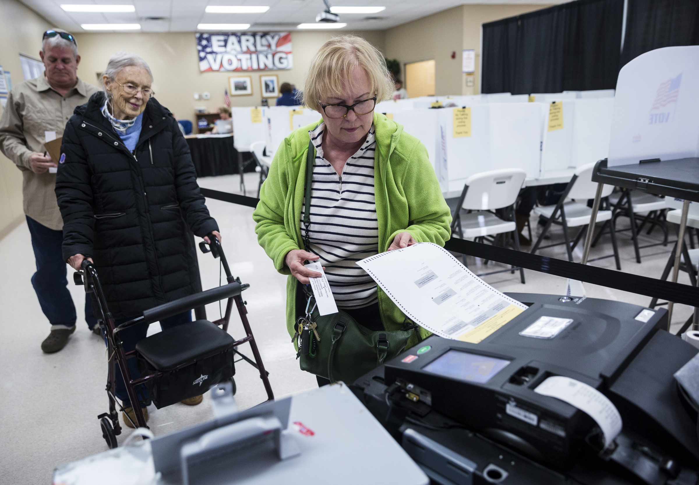 Rosemary Milburn, right, places a paper ballot into a voting machine for her mother Garvin Colburn, center, during early voting at the Hamilton County Election Commission on Amnicola Highway on Saturday, Oct. 22, 2016, in Chattanooga, Tenn.