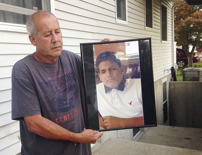 In this Sept. 27, 2016 file photo, Abraham Chaparro, holds a photograph of his murdered stepson, Miguel Garcia-Moran, outside his home in Brentwood, N.Y. Garcia-Moran is among four teenagers from Brentwood High School that have been found dead this past month in a string of brutal killings that assistant Suffolk County Police Commissioner Justin Meyers says may be tied to gang violence. (AP Photo/Claudia Torrens, File)