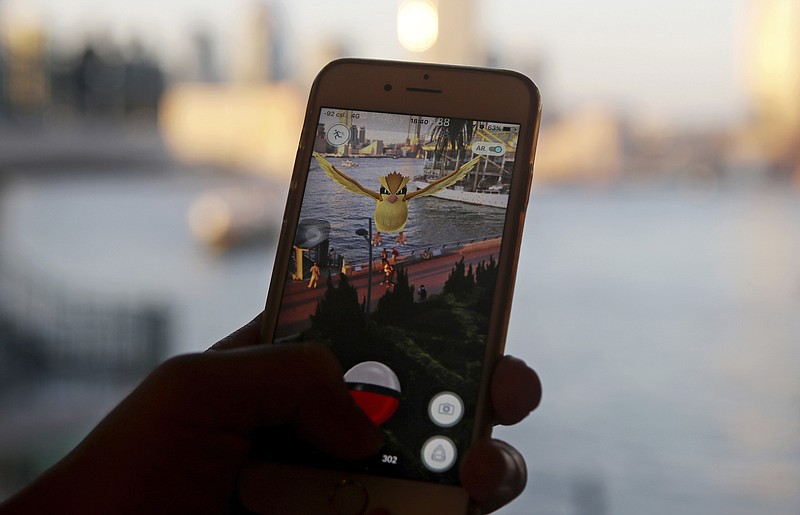
              FILE - In this July 25, 2016, file photo, a fan maneuvers his smartphone as he plays "Pokemon Go" in Hong Kong. Japanese video game maker Nintendo Co. slashed its operating profit and sales forecasts for this fiscal year, despite the global success of “Pokemon Go.” The maker of Super Mario games and the Wii U console said Wednesday, Oct. 26, 2016, that it booked a 62.7 billion yen ($601.7 million) gain in April-September from its sale of the Seattle Mariners Major League Baseball team. (AP Photo/Kin Cheung, File)
            