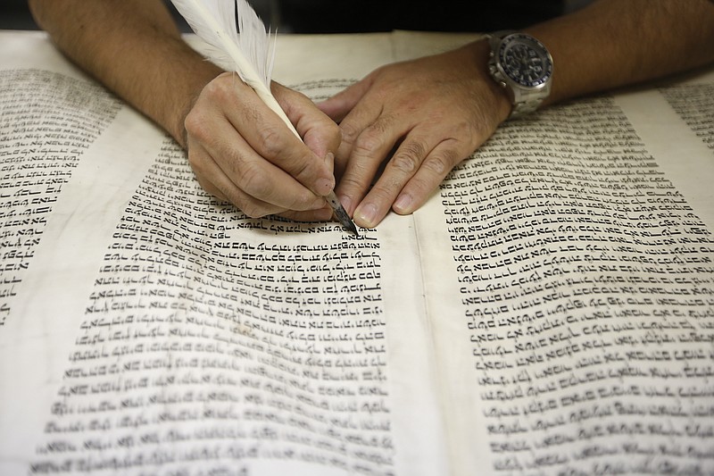 Rabbi Yochanan Salazar, a sofer whose duty is to scribe and maintain the Torah, uses a quill to re-scribe text in a 100-year-old Torah on Tuesday, Aug. 19, 2014, at B'nai Zion Synagogue in Chattanooga, Tenn. Torah scrolls must be maintained, or kept kosher, as wear from their use stains the parchment or blemishes the hebrew script.