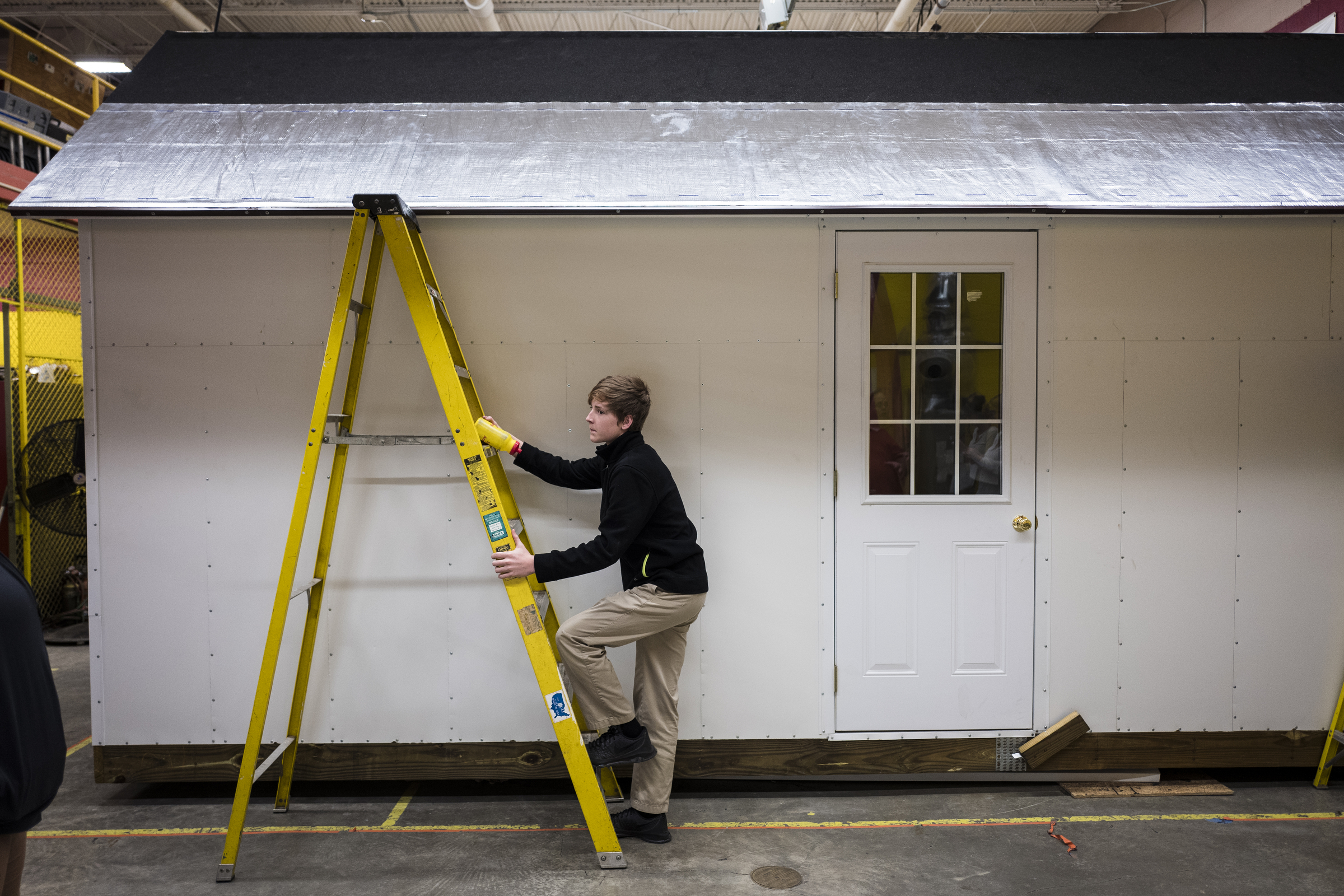 Gage Swanson climbs a ladder to flatten out reflective roofing material on a Tiny House under construction at Tyner Academy on Wednesday, Oct. 26, 2016, in Chattanooga, Tenn. Students in Jerry Webb's class have been constructing the environmentally friendly Tiny House, which will include a solar power system, to learn about renewable energy and sustainability.