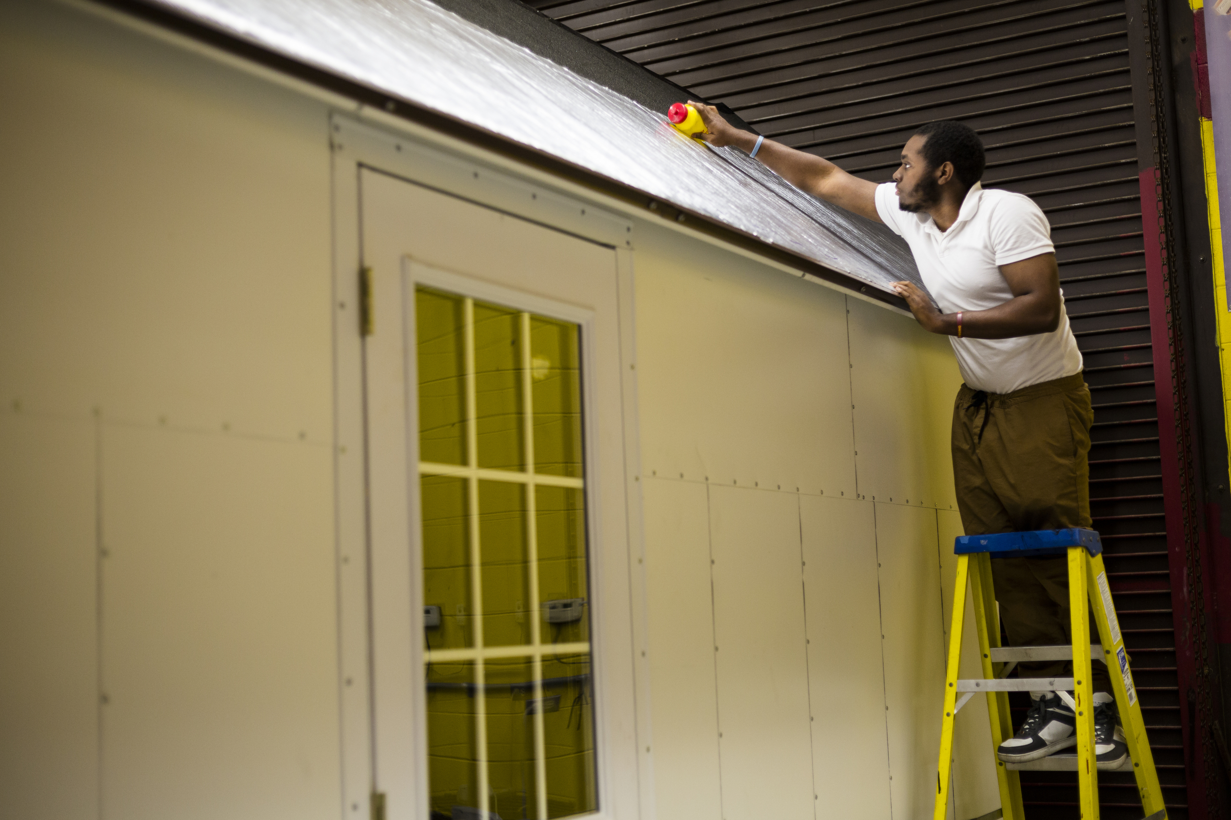 Devin Davis flattens out reflective solar roofing material on a Tiny House under construction at Tyner Academy on Wednesday, Oct. 26, 2016, in Chattanooga, Tenn. Students in Jerry Webb's class have been constructing the environmentally friendly Tiny House, which will include a solar power system, to learn about renewable energy and sustainability.