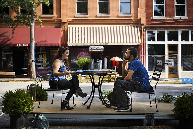 Allison Reedy, left, and Ian Tejeda talk on a patio set up in a parking space on Martin Luther King, Jr., Boulevard at the annual PARK(ing) Day event on Friday, Sept. 16, 2016, in Chattanooga.