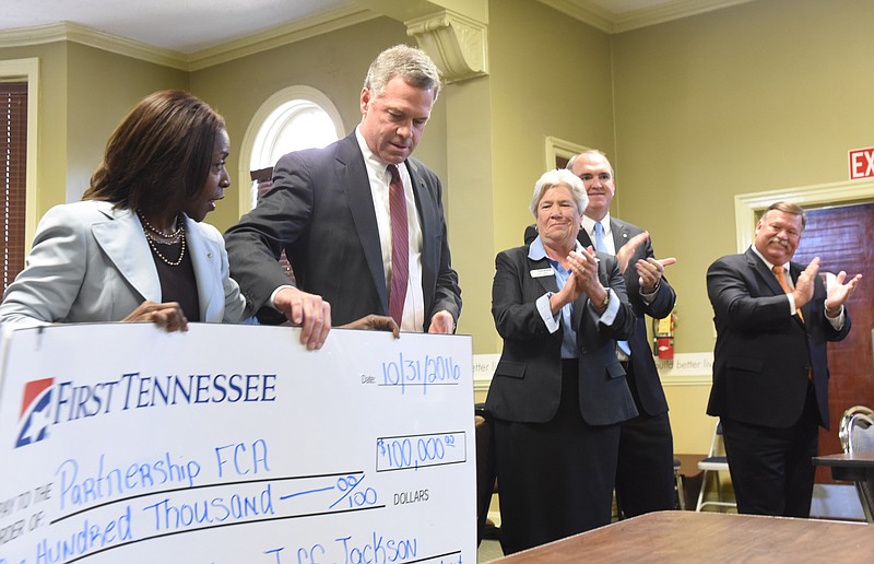 First Tennessee Community Development Manager Tracee Smith, left, displays a gift check with Bryan Jordan, CEO and President of First Horizon, after the announcement of a $100,000 gift to Partnership for Families to be used for home ownership down payments. Partnership CEO Pam Ladd, center, Jeff Jackson and Hamilton County Mayor Jim Coppinger applaud the gift.