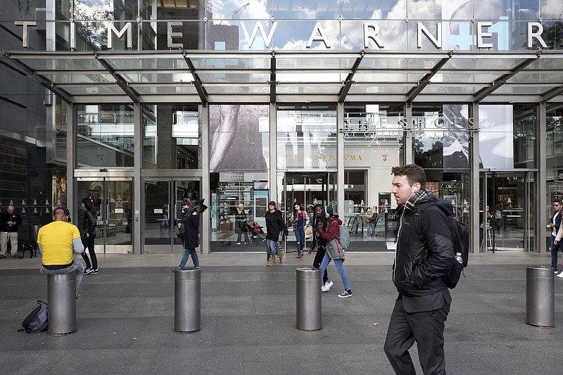 
              FILE - In this Monday, Oct. 24, 2016, file photo, people walk past the Time Warner building, in New York. Time Warner reports financial results Wednesday, Nov. 2, 2016. (AP Photo/Mark Lennihan, File)
            