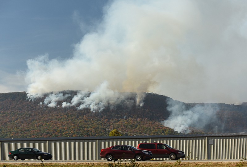 Northbound traffic on U.S. Highway 27 passes the forest fire at Flipper Bend near the North Chickamauga Creek in Soddy-Daisy late Monday. Crews from Tennessee State Parks, the Tennessee Department of Agriculture Forestry Division and U.S. Forestry Service personnel from the Bureau of Land Management were on scene as two Air National Guard BlackHawk helicopters sporadically dumped water on the expanding blaze.