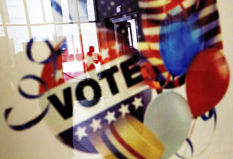 In this Nov. 1, 2016, photo, a voter is reflected in the glass frame of a poster while leaving a polling site in Atlanta, during early voting ahead of the Nov. 8 election day.