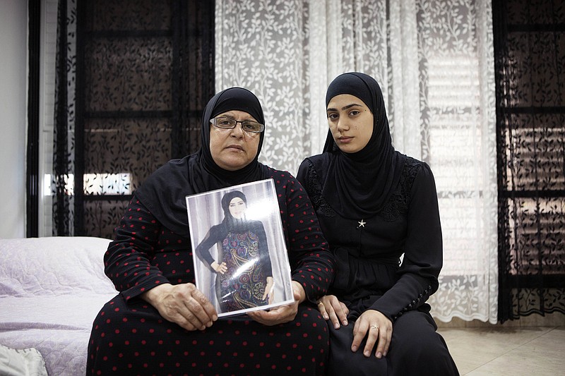 
              In this photo taken Thursday, Nov. 3, 2016. Israeli Arab Majeda Abu Sharkh left, holds a picture of Duaa Abu Sharkh that was killed in Lod as she poses for a photograph with her niece Alaa Khalili, in Lod, central Israel. After years of abuse and death threats, Duaa Abu-Sharkh had finally divorced her husband, agreeing even to give up custody of her four young children to escape his violent grip. Then, one night in late September, as she was dropping off her kids after a rare visitation, a masked gunman dragged her from her car in the center of this crime-ridden city and shot her in the head before their eyes.  (AP Photo/Dan Balilty)
            