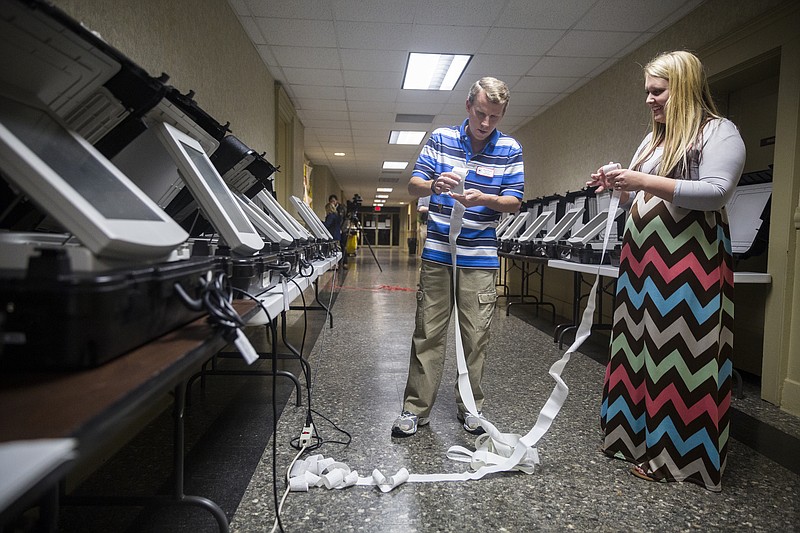 Chuck Fletcher, left, and Brittany Richardson roll up paper records of electronic voting at the Walker County Courthouse on Tuesday, Nov. 8, 2016, in Lafayette, Ga.