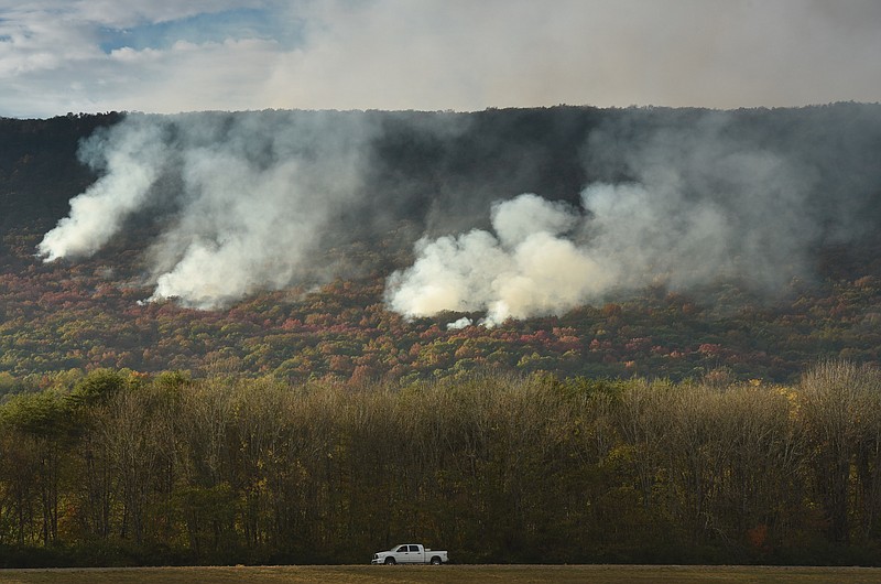 A southbound pickup is dwarfed by the white smoke from the Flipper Bend fire late Tuesday in view of U.S. Highway 27, in Soddy-Daisy.