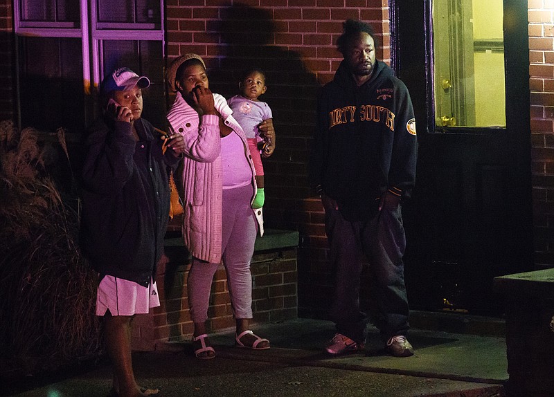 Bystanders in a neighboring apartment observe the scene of a shooting at The Pinewood apartments on Pinewood Avenue that sent one victim to the hospital early in the evening Thursday, Nov. 10, 2016, in Chattanooga, Tenn. Police on the scene said the victim was transported by a personal vehicle.