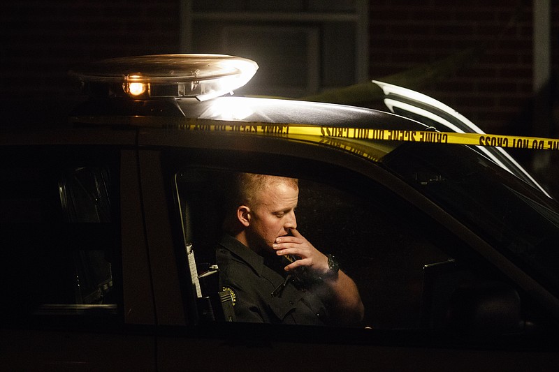 A Chattanooga police officer works inside his patrol car at the scene of a shooting at The Pinewood apartments on Pinewood Avenue that sent one victim to the hospital early in the evening Thursday, Nov. 10, 2016, in Chattanooga, Tenn. Police on the scene said the victim was transported by a personal vehicle.