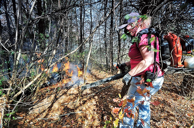 Volunteer firefighter's Sheri Torbett, with the Sequoyah Volunteer Fire Department, uses a leaf blower Thursday to turn back approaching flames near the Mobray Volunteer Fire Hall in Soddy-Daisy.