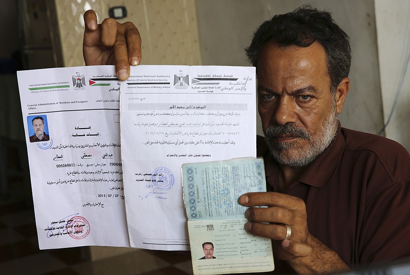 
              In this Oct. 31, 2016 photo, Syrian refugee, Majed al-Attar, poses while showing his expired Syrian passport and Palestinian identification documents at his family's rented house in Rafah, Gaza. Like millions of Syrians, the al-Attar family fled the civil war in his homeland in search of safety and security, but in a decision they now regret, they chose to go to Gaza. The al-Attar family is among 12 Syrian households that found refuge in Gaza after the civil war erupted in 2011 and are now trapped in the war-battered territory, but also unable to travel abroad. (AP Photo/Adel Hana)
            