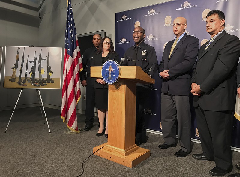 Los Angeles Police Cmdr. Horace Frank, third from left, is joined by Omar Ricci, Spokesperson Islamic Center of Southern California, second from right, and Mahomed Akbar Khan, far right, as police shows a photo of multiple weapons found in the home of a man charged with making terrorist threats to the Islamic Center of Southern California, during a police news conference Tuesday, Oct. 25, 2016 in Los Angeles. Mark Lucian Feigin was arrested last week on the charge, which has been designated as a hate crime, according to authorities. Feigin, 40, has been released on bail. Police say Feigin first called the Islamic center Sept. 19 and left a hate-filled voicemail. The next day, they say, he called and threatened to kill people at the center.