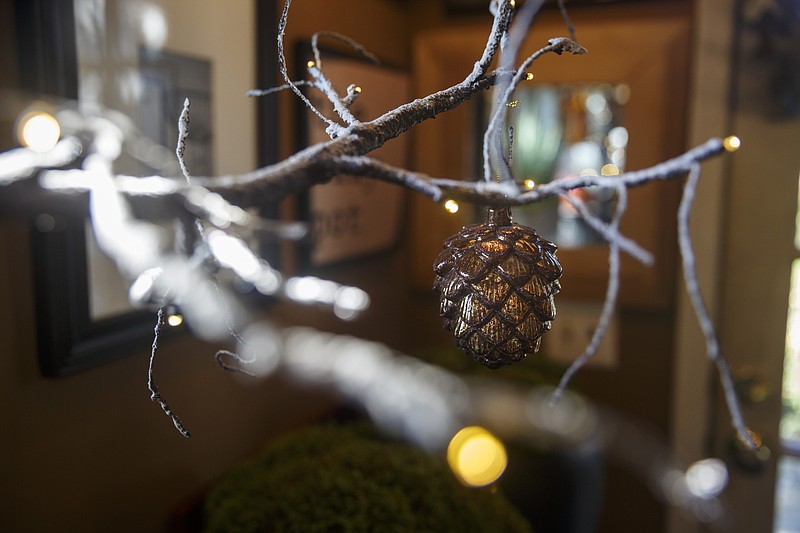 Bronze, mercury-glass pine cones decorate this twig tree. Pine cone ornaments and light strands are an easy update to the popular woodland-themed decor. Design by The Clay Pot.
