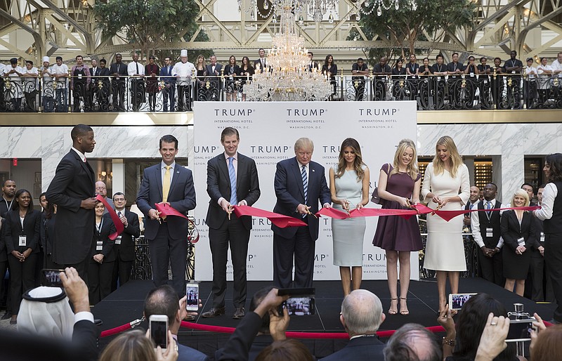 Donald Trump, center, cuts the ribbon with his wife and children during the opening ceremony at Trump International Hotel in Washington on Oct. 26. One issue of Trump's presidency is likely to be the potential conflicts of interest on multiple fronts, from tax policy to debt the president-elect owes to various banks and foreign business entanglements.