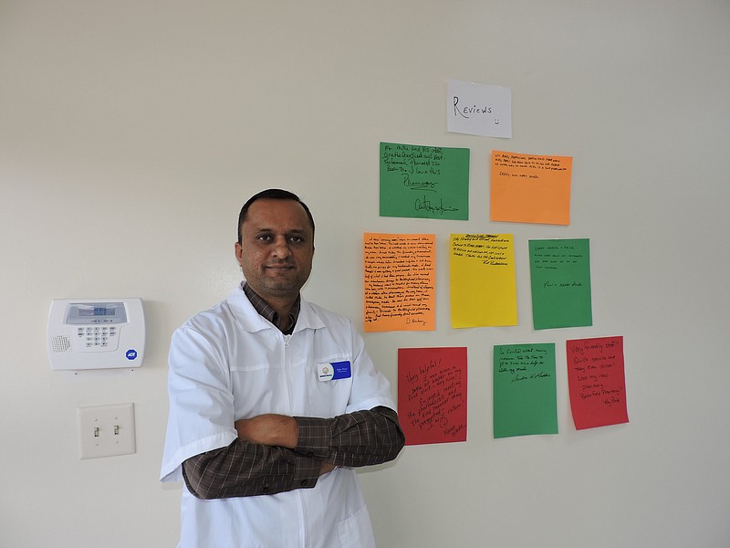 Battlefield Pharmacy owner Mike Patel prides himself on personalized customer service. Here, he stands beside some of the positive comments customers have left for him.