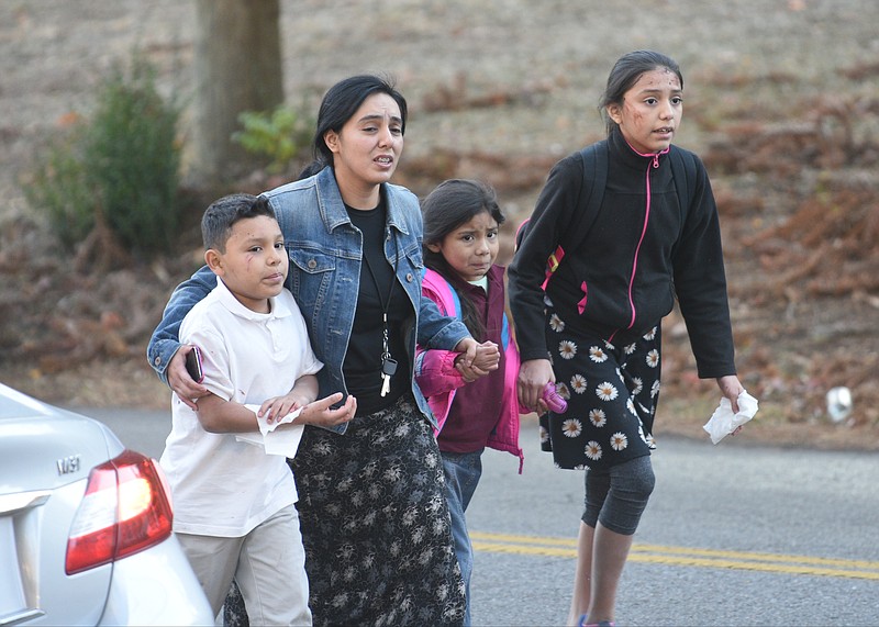 A woman escorts three children away from the scene of a school bus wreck involving multiple fatalities on Talley Road in Chattanooga, Tenn., Monday, Nov. 21, 2016. 