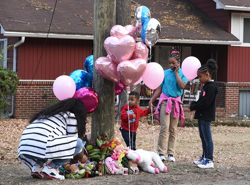 Terrance Hayes, Takayla Robinson and Ha-Rhiya Bennett, from left, watch as a woman who declined to be named places balloons at a memorial on Talley Road Tuesday, Nov. 22, 2016. Balloons and stuffed animals have been left to honor six students who were killed when their school bus crashed Monday, Nov. 21, 2016. Bennett attends Woodmore Elementary School.