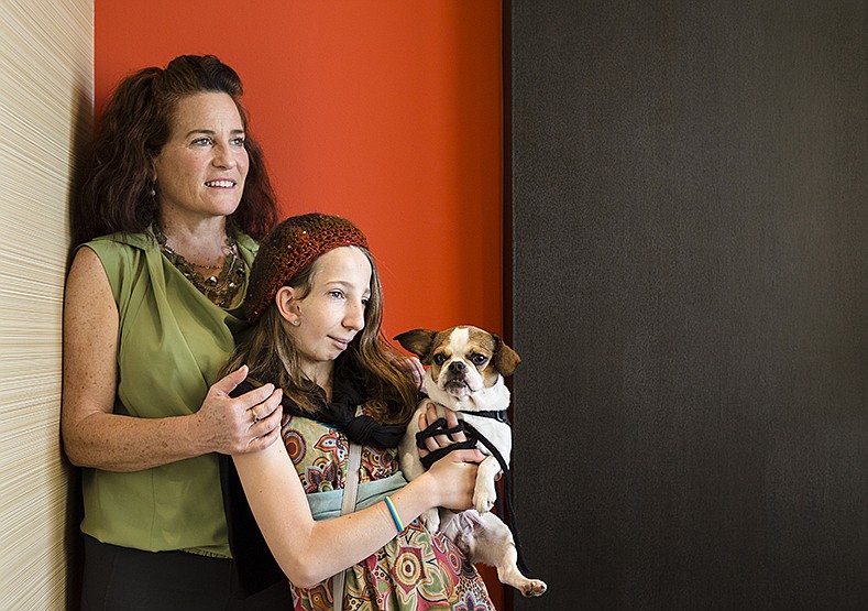 Amy Schefer stands with her daughter, Elena, and service dog Tuki in the Courtyard Marriott near Hamilton Place, where they stayed while in town for a fundraiser for FACES: The National Craniofacial Association.