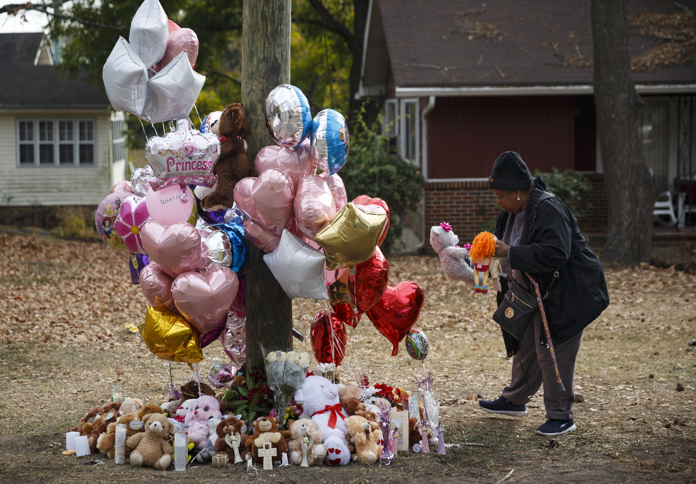 Neighborhood resident Michelle Ingram places a teddy bear in memory of victims at the site of a fatal school bus crash on Talley Road on Wednesday, Nov. 23, 2016, in Chattanooga, Tenn. The makeshift memorial to victims of the Monday crash, which killed 5 Woodmore Elementary students and injured dozens more, has grown since the road was reopened Tuesday.