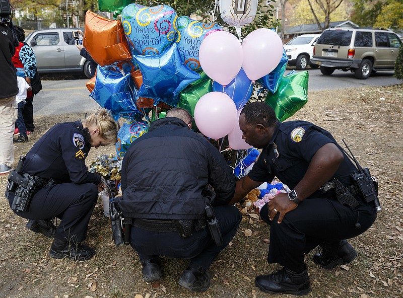 Three Chattanooga Police Officers, who requested that their names not be used but said that they were the first three officers to arrive on scene, bring balloons and a stuffed animal to leave at the site of a fatal school bus crash on Talley Road on Wednesday, Nov. 23, 2016, in Chattanooga, Tenn. The makeshift memorial to victims of the Monday crash, which killed 5 Woodmore Elementary students and injured dozens more, has grown since the road was reopened Tuesday.