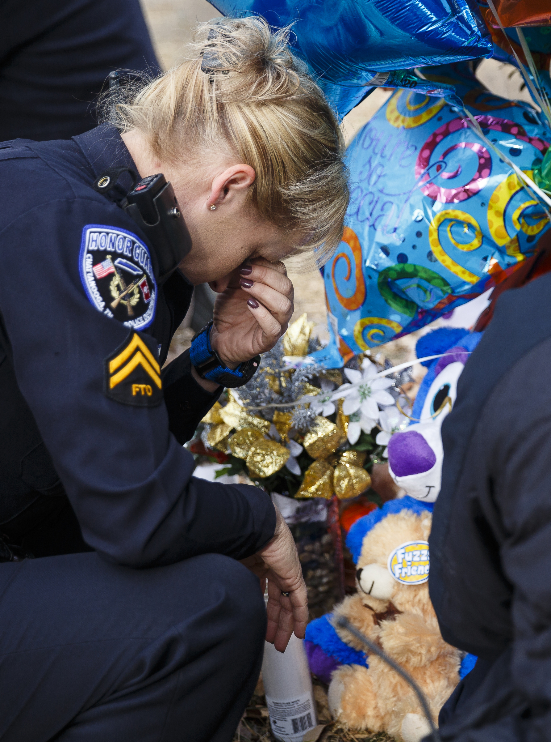 A Chattanooga Police Officers, who requested that her name not be used but said that she was among the first three officers to arrive on scene, reacts after leaving balloons and a stuffed animal at the site of a fatal school bus crash on Talley Road on Wednesday, Nov. 23, 2016, in Chattanooga, Tenn. The makeshift memorial to victims of the Monday crash, which killed 5 Woodmore Elementary students and injured dozens more, has grown since the road was reopened Tuesday.