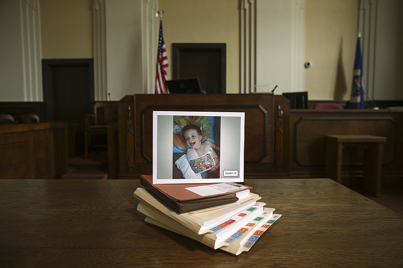 
              FILE - This July 15, 2014 file photo shows a photograph of Eric Dean, with a broken arm, placed on folders of exhibits and documents presented in court in Glenwood, Minn., relating to the May 2014 trial of Amanda Peltier in the death of her 4-year-old stepson, Eric. In 2014, the Minneapolis Star-Tribune ran an in-depth story reporting how Eric's plight drew little scrutiny despite 15 separate abuse reports being lodged with social workers. In response, Gov. Mark Dayton ordered closer oversight of child-protection decisions and formed a task force that recommended dozens of steps to place more emphasis on child safety. (Jeff Wheeler/Star Tribune via AP)
            