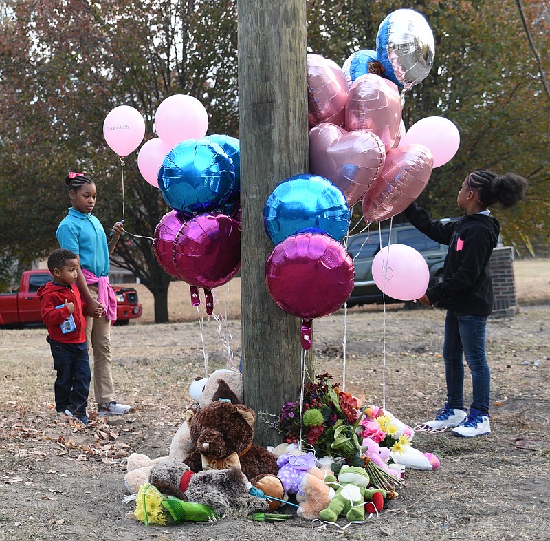 Staff Photo by Angela Lewis Foster Terrance Hayes, Takayla Robinson and Ha-Rhiya Bennett, from left, place balloons at a memorial on Talley Road Tuesday, Nov. 22, 2016. Balloons and stuffed animals have been left to honor five students who were killed when their school bus crashed Monday, Nov. 21, 2016. Bennett attends Woodmore Elementary School.